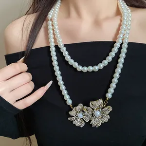 Elegant vintage double-strand pearl necklace featuring sparkling rhinestone flower pendants