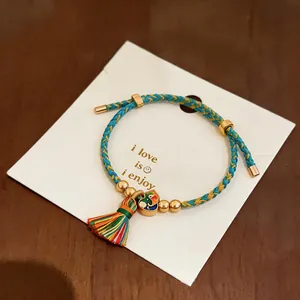 Detailansicht eines bunt geflochtenen Armbands mit Seidenquaste und Goldperlen