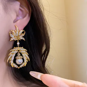 Close-up detail of retro maple leaf pendant earrings with sparkling zircons and pearl.