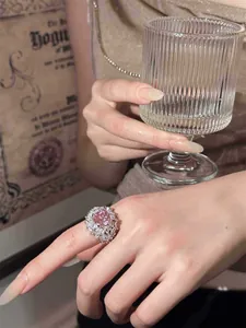 Close-up detail of luxury pink zircon open ring worn by model holding a glass