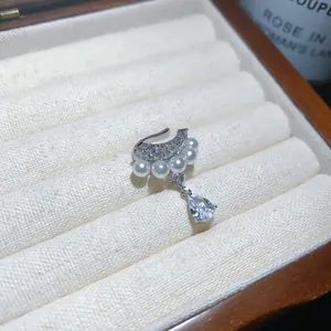 Close-up detail of silver ear cuff with pearls and waterdrop zircon in a jewelry box.