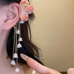 Primo piano di elegante ear cuff con fiore in tessuto e lunghe nappe di perle