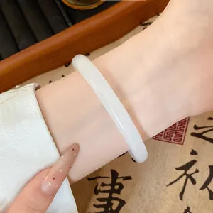 Close-up of elegant white glass bangle with smooth round jade-like finish on wrist