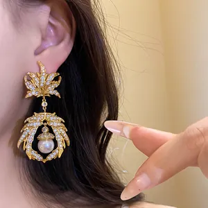 Detailed macro view of a luxury vintage gold maple leaf earring with zircons and a white pearl
