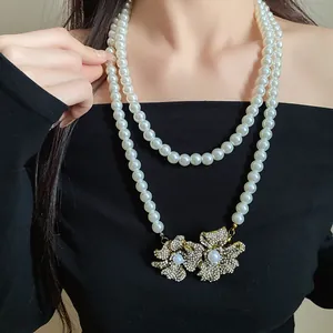 Close-up of vintage double-layer pearl necklace with rhinestone flower charms.