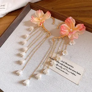 Dettaglio di ear cuff a fiori con lunghe nappe di perle su espositore