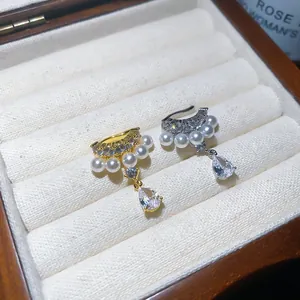 Close-up of gold and silver plated zircon and pearl water drop ear cuffs in a velvet box