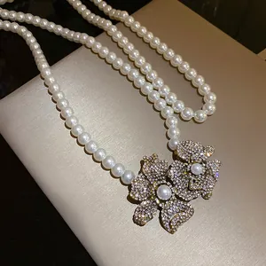 Macro view of crystal-encrusted flower pendant on a double-strand pearl necklace.