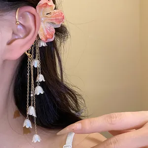 Dettaglio dell'orecchino con fiore in tessuto e nappe a mughetto in stile dolce
