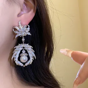 Close-up of luxury zircon maple leaf dangle earrings with white pearl on a model's ear