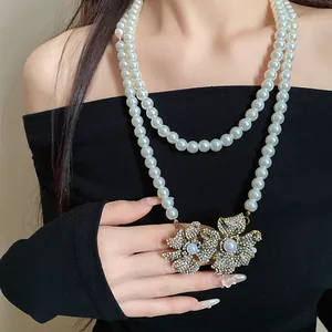 Detail of vintage double-layer pearl necklace with rhinestone flower pendant on model.