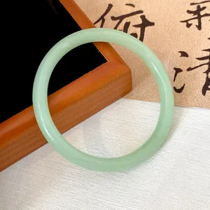 Macro detail of a light green translucent glass bangle with smooth round profile.