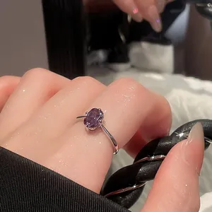 Close-up of a vintage-style silver open ring featuring a stunning oval purple gemstone.