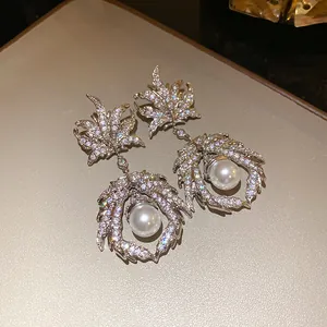 Close-up of vintage silver-tone maple leaf dangle earrings with zircons and pearls