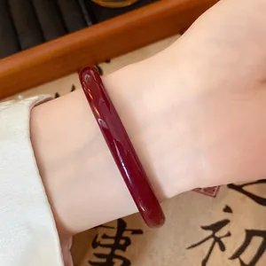 Detailed view of a glossy dark red glass bangle worn on a wrist with traditional style