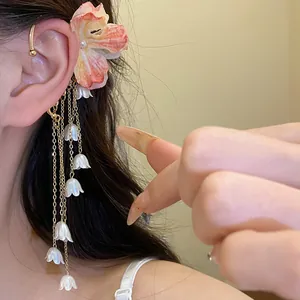 Dettaglio di un elegante ear cuff con fiore in tessuto e nappa di perle su modella