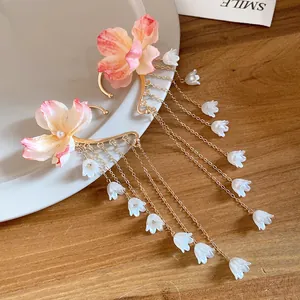 Dettaglio di eleganti copriorecchi a fiori con lunghe nappe di mughetto dorate