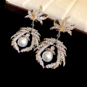 Macro view of vintage maple leaf dangle earrings encrusted with zircons and a white pearl