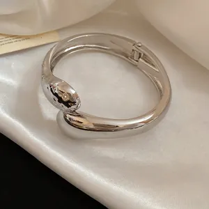 Close-up detail of a chic textured silver metal bangle with an elegant hinged clasp design