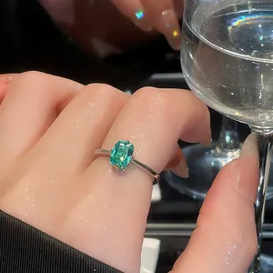 Close-up of emerald cut green gemstone open ring on finger