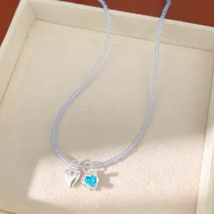 Detail view of blue beaded necklace with silver heart and zircon pendants in a tray