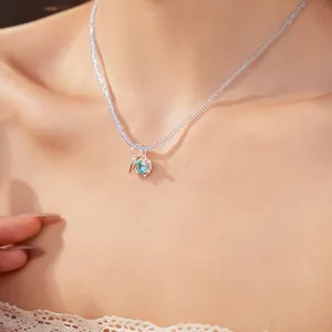 Detail view of a beaded necklace featuring a light blue heart-shaped zircon pendant.