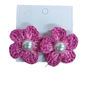 Orecchini a fiore intrecciato rosa fatti a mano con grandi perle su carta bianca