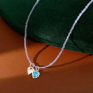 Detailed close-up of heart-shaped blue zircon pendant on glass beaded necklace