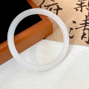 Close-up of a elegant white imitation jade glass bangle on a decorative background