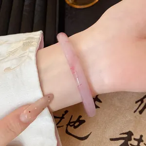 Detailed view of a translucent dry rose pink glass bangle worn with traditional Hanfu