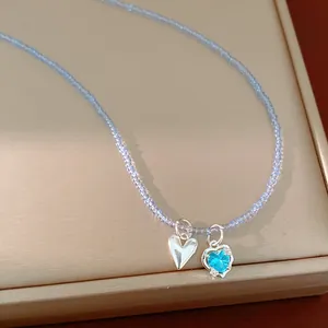 Detail view of a glass beaded necklace with silver heart and blue heart zircon charms.