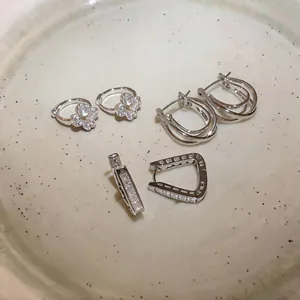 Close-up detail of silver-toned zircon earrings in various geometric and floral designs