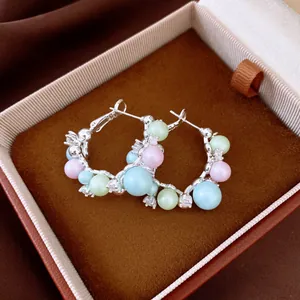 Gros plan de créoles en argent avec perles pastel et détails en zircone cubique
