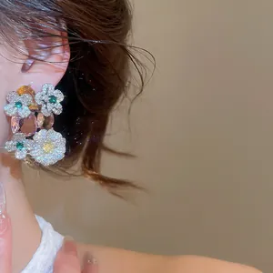 Close-up of zircon flower oval pendant earrings worn on ear showing sparkly details.