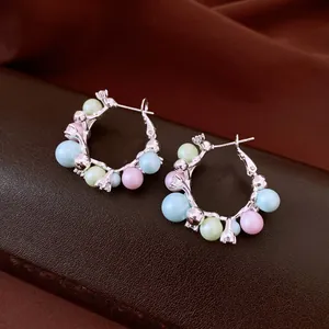 Vue détaillée de boucles d'oreilles créoles en argent avec perles pastel et zircons.
