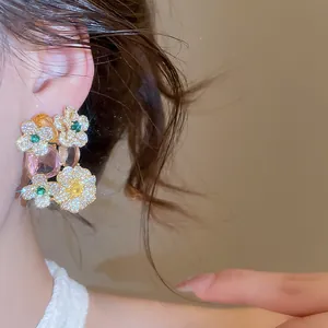 Macro view of elegant floral drop earrings with zircons and pink gemstones on ear