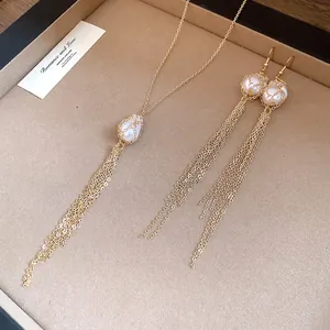 Macro detail of gold chain tassel earrings and mesh-wrapped pearl necklace set