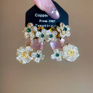 Close-up of elegant sparkling zircon flower earrings with pink oval stone pendants