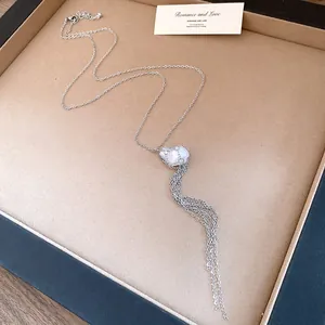 Close-up of elegant silver necklace with pearl pendant and long tassel detail for women