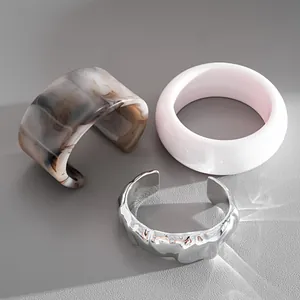 Vista dettagliata del polsino in metallo argento con bracciali in acrilico marmo e rosa