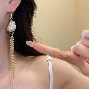 Close-up of vintage gold tassel earrings featuring a large baroque pearl in a metal cage