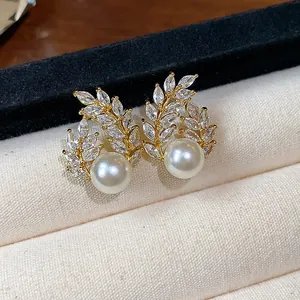 Detailed view of gold-plated wheat ear pearl earrings with cubic zirconia inlay