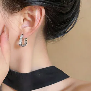 Detailed view of elegant French style U-shaped zircon hoop earrings worn on a model ear