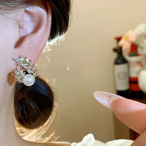 Detailed view of 18k gold-plated wheat spike earring with pearl on model's ear