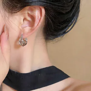 Close-up detail of silver multi-strand hollow hoop earrings worn on a model's ear
