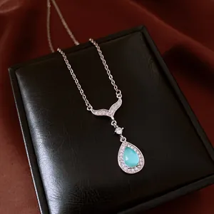 Élégant collier avec pendentif goutte bleue et détail queue de poisson sur boîte en cuir noir