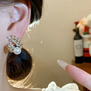 Close-up detail of elegant 18k gold plated wheat spike earring with crystals and white pearl