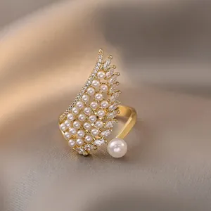 Vista detallada de un elegante anillo de ala dorado decorado con perlas y circonitas finas