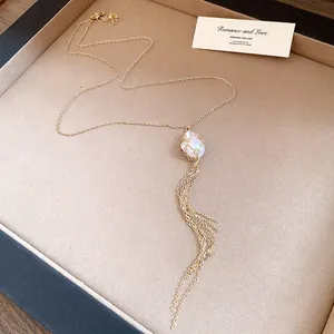 Close-up of elegant gold chain necklace featuring a baroque pearl and long tassels