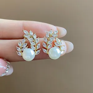 Close-up of elegant 18k gold-plated wheat-ear stud earrings featuring pearls and marquise-cut stones